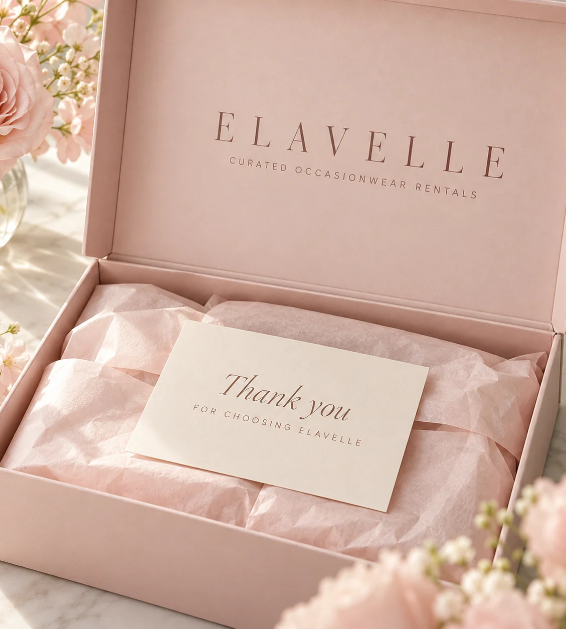 An Elavelle box, opened, with pink tissue and a thank-you card